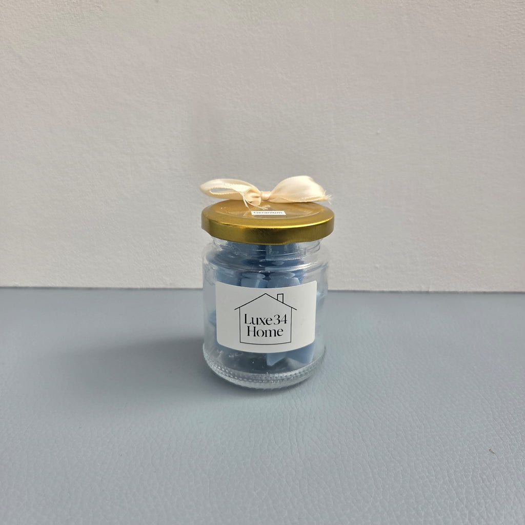 Two Luxe 34 Home geranium wax melt jars showing front and back labels with gold lids`