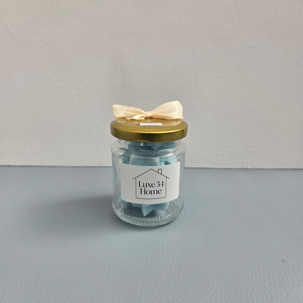Two Luxe 34 Home geranium wax melt jars showing front and back labels with gold lids`