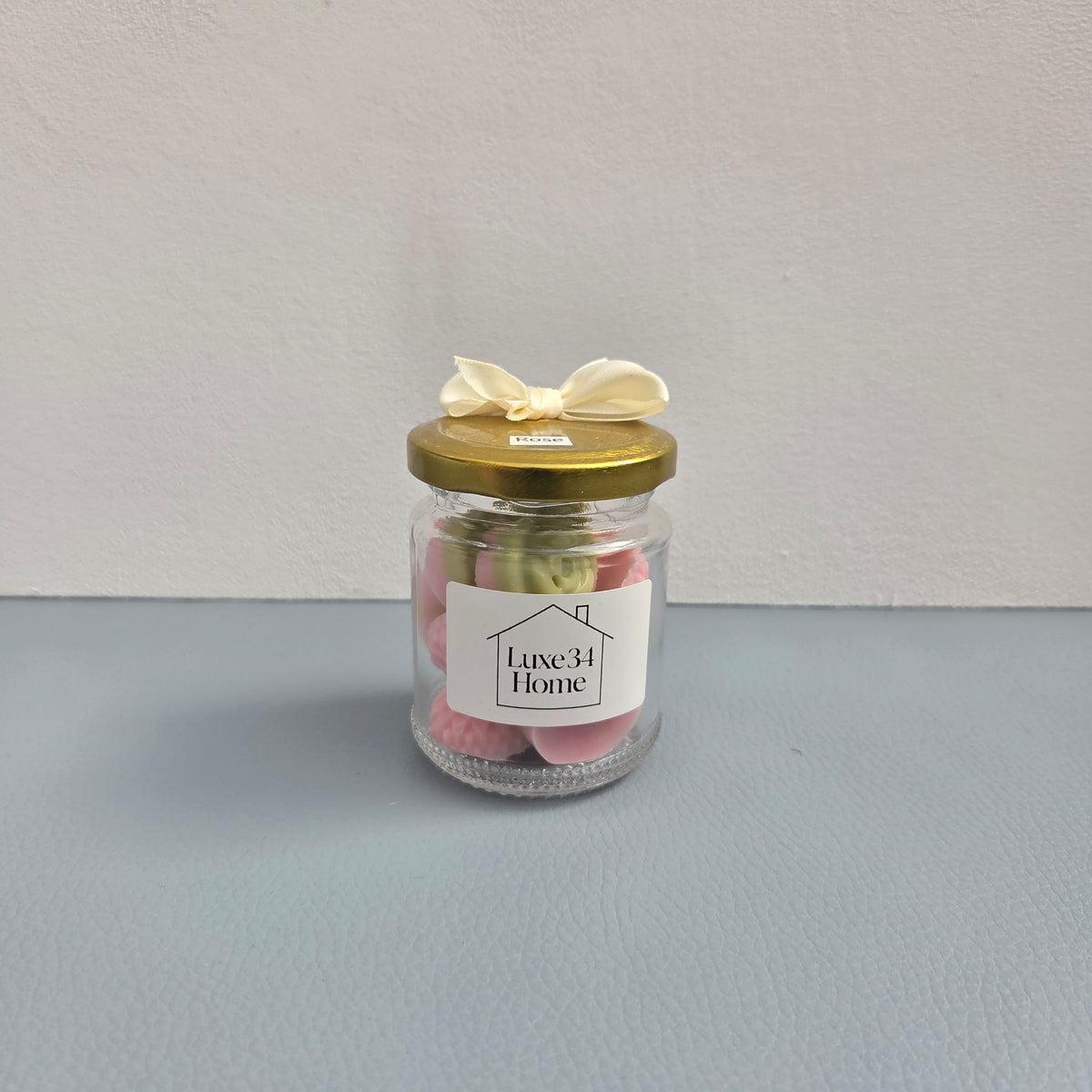 Luxe 34 Home rose wax melts close up in glass jar with pink and green rose-shaped wax melts and gold lid