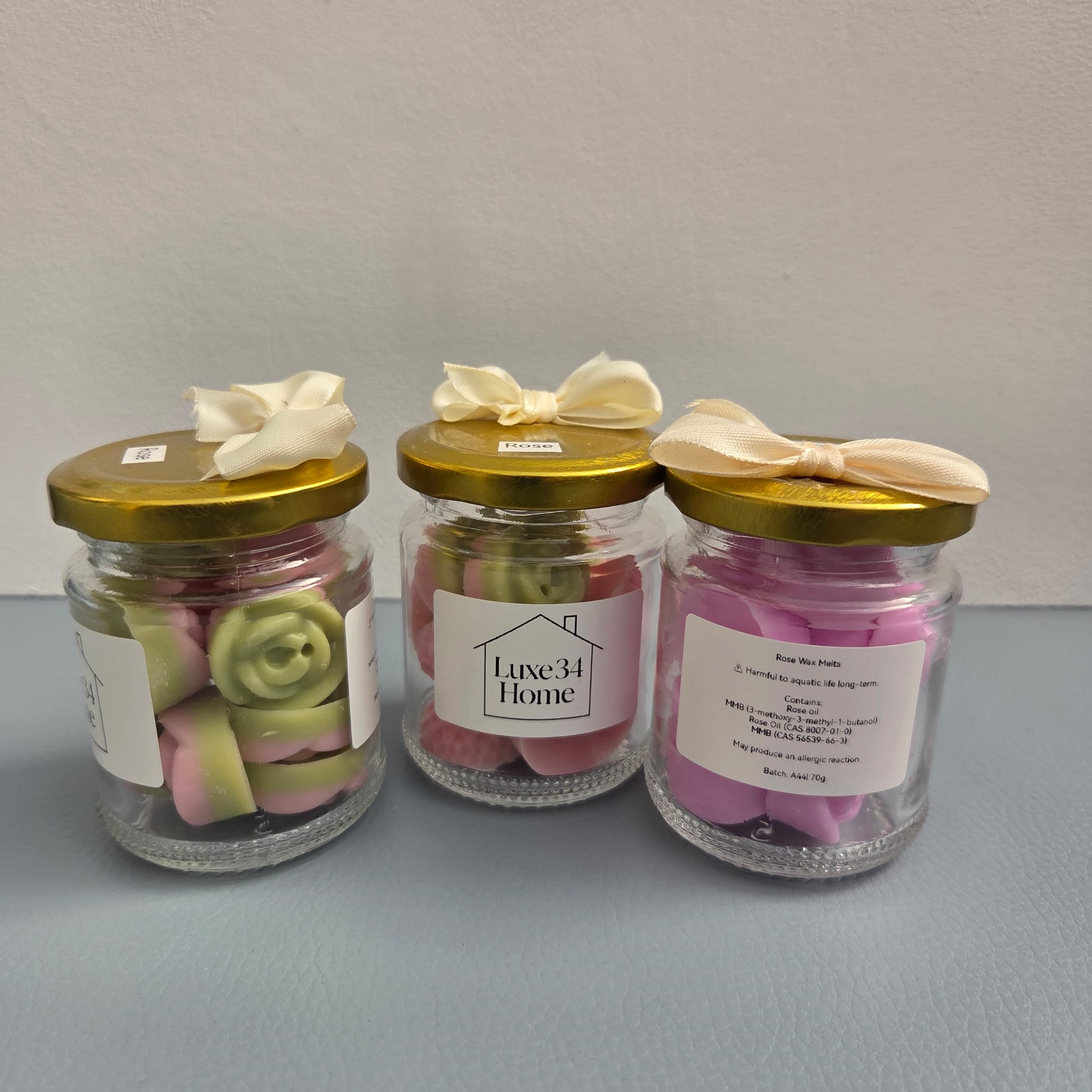 Three Luxe 34 Home rose wax melt jars showing the range with pink and green rose-shaped wax melts