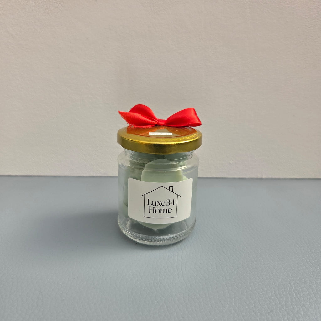 Luxe 34 Home pine needle wax melts in glass jar with sage green wax melts, gold lid and red ribbon bow