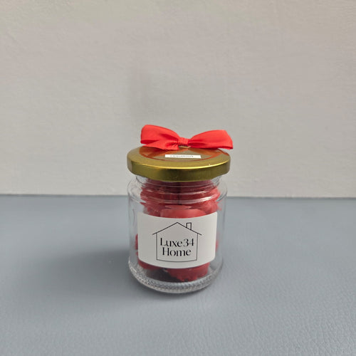 Luxe 34 Home cinnamon wax melts in glass jar with deep red wax melts, gold lid and red ribbon bow